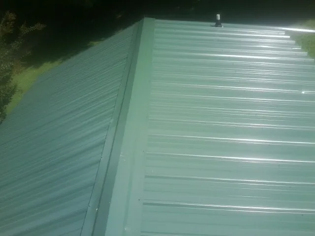 New green metal panels meeting at the ridge of a roof — Flat Roof Repair work by our crew in Vincentown