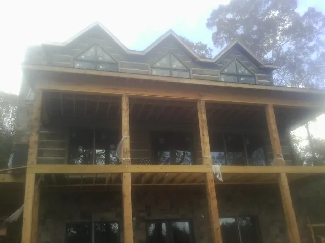 Dormers and porch framing on a large log home under construction — Roof Coating work by our crew in Vincentown
