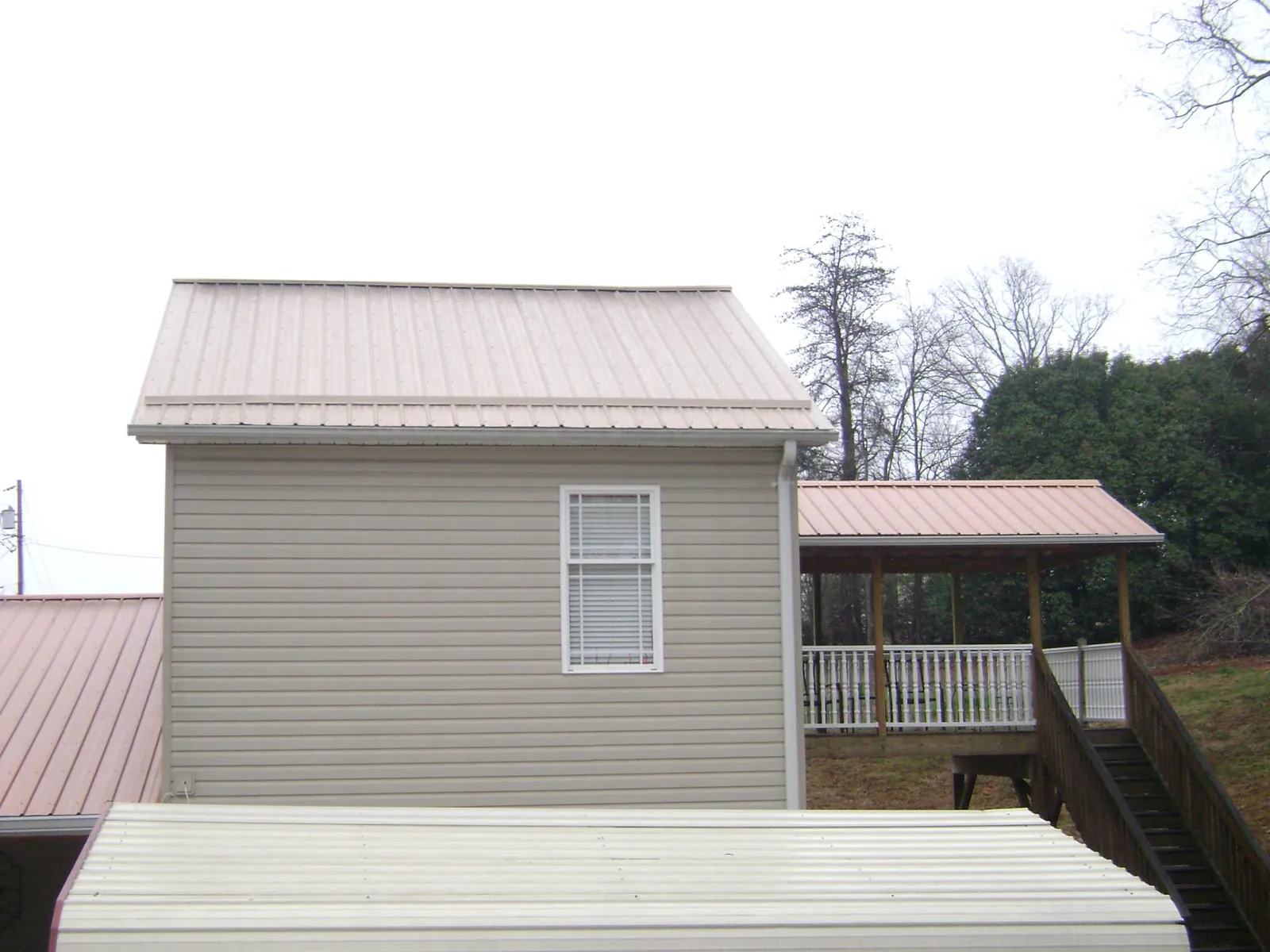 Tan metal roofs on a two story addition and attached porch, from a Roof Replacement job in Vincentown