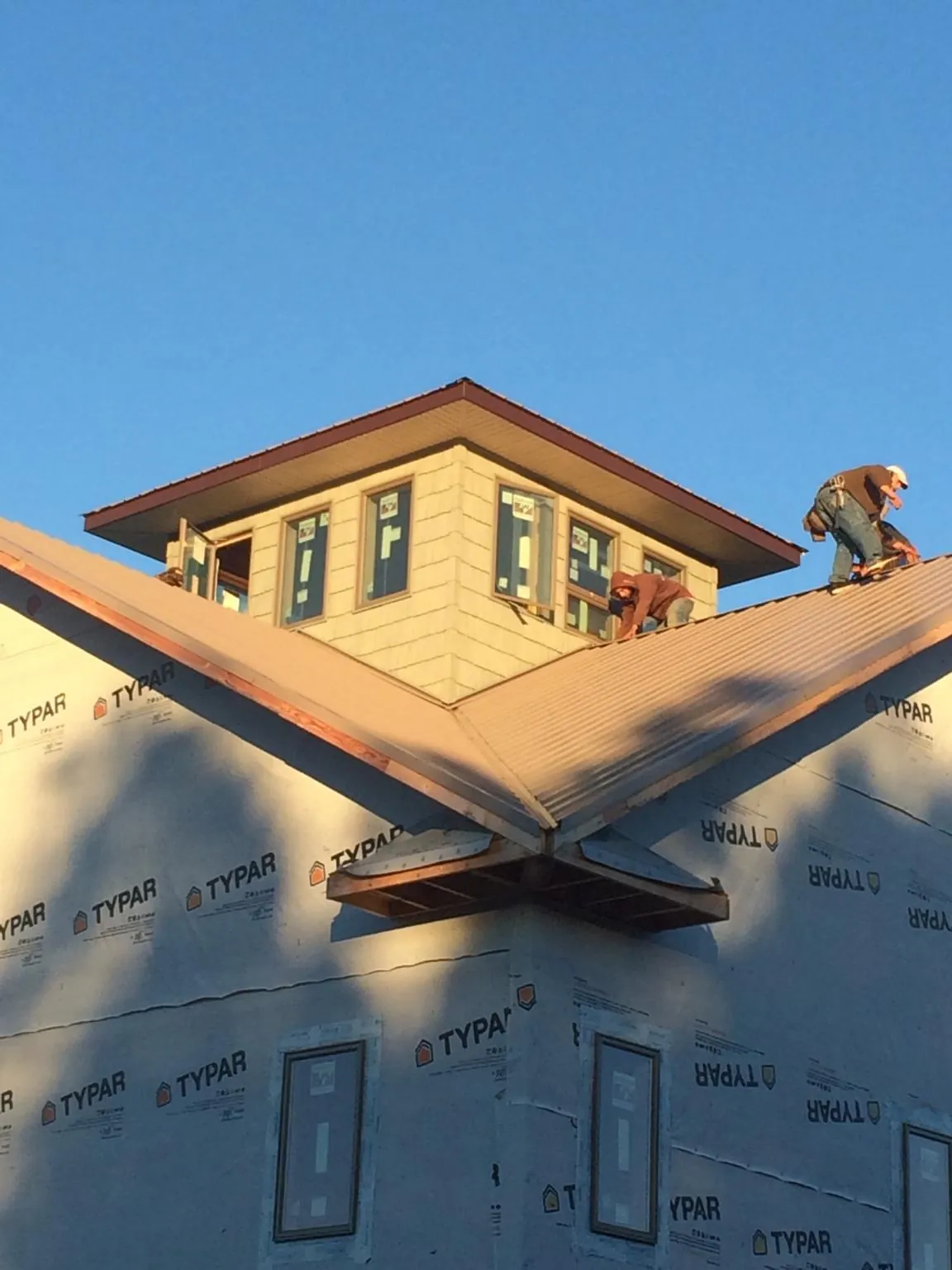 Roofers working around a rooftop cupola on a new metal roof at sunset — Roof Waterproofing in Vincentown by Roofing Brothers